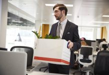 Fired male employee holding box of belongings in an office