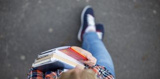 Student lady with a heap of textbooks and notebooks