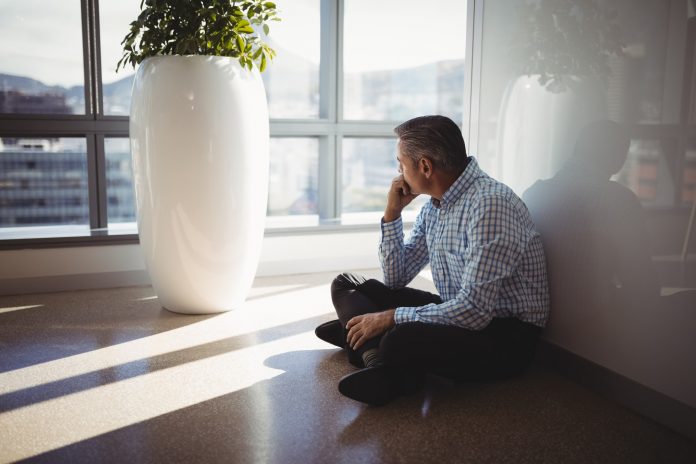 Thoughtful executive sitting on floor