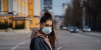Girl in protective mask using smartphone outdoors. COVID 19. World coronavirus pandemic