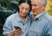 Mujer enseñándole al señor mayor a usar los aparatos electrónicos para abuelitos